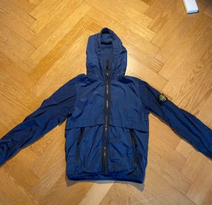 Stone island jacka  - Det är en stone island jacka i färgen blå. Den är i stolek 142. Jag säljer den för att den är förliten men det är fortfarande jättebra skick. 