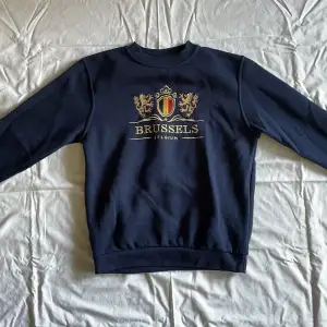 Marinblå sweatshirt med broderat tryck i stl S. Aldrig använd och har inga defekter.