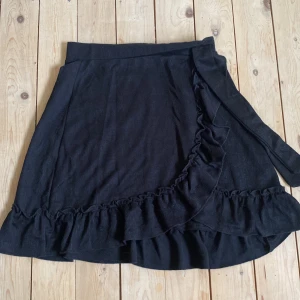 Volangkjol - Svart volangkjol med knyte i sidan. Aldrig använd. 