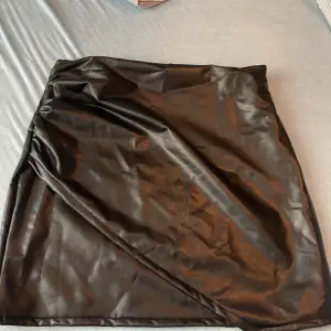 svart minikjol i ”läder” material med ett sorts överdrag fram