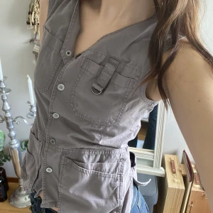 Grå väst  - Snygg grå väst från Hejco med många detaljer, spännen vid midjan så man kan reglera. Fint skick! 