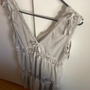Miniklänning - Säljer denna sjukt vackra gråa miniklänningen med jättefina rosetter och spetsdetaljer, då den tyvärr var för kort på mig (som är typ 163cm). Köpt second hand men prislapp kvar! 