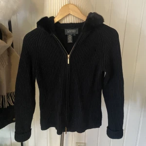 Ralph Lauren tjocktröja - Supersnygg tjocktröja med dragkedja i guld från Ralph Lauren. Svart med pälsimitation runt luva. 🫶 vintage plagg som inte säljs längre. Storlek S. Gjord på 87% ull och 13% kashmir, därmed supermjuk och värmande. 💕 Litet hål fram men inte så märkbart. 