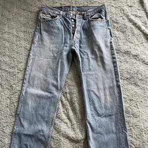 Blåa jeans från Levis, modell 501 med knappgylf. Säljes då de inte längre används.