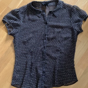 Skjorta - En kortärmad svart skjorta med vita detaljer från H&M. Så gott som nyskick. 