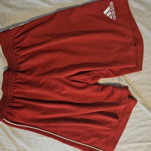 Adidas shorts - Bekväma träningsshorts och fräckare färg. Nåot små hål är lagat men inget som påverkar eller syns.