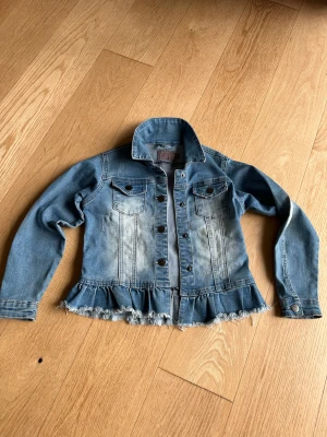 Jeansjacka - Creamie - stl 134 - Jättefin jeansjacka i mjukt och strechigt jeans material. Tryckknappar och liten volang som gör den feminin. Knappt använd då den tyvärr snabbt  blev för liten. 