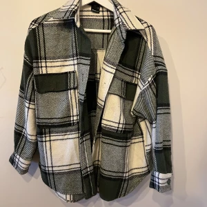 Flannel Shirt Stl.XS Mörkgrön/svart - Något för kort i ärmarna på mig.  Rutig skjorta med bröstfickor. Skjortan är mörkt grön/svart och långärmad med krage. Den har knappar framtill och på fickorna.  Nypris 399:-