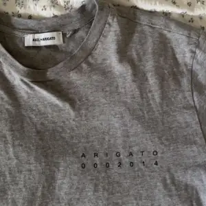 Grå T-shirt från Axel Arigato med text fram & tryck bak. Skulle säga att den är i storlek S/M🦜