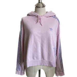 Adidas hoodie  - En rosa croppad adidashoodie som köptes för några år sedan men aldrig använts. Fina lila broderade blommor på sidan. Perfekt skick i strl S