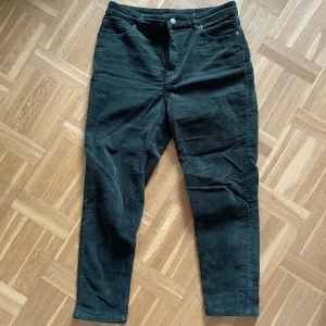 Manchesterbyxa  - Mörkgröna manchesterbyxor från Monki i storlek 42. Använda ca 2 ggr, fint skick.  Något stora på mig. Har vanligtvis storlek 40 på underdelar. Mitt midjemått är 74-77, stuss 98 för referens.