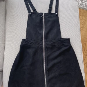 Svart hängselklänning  - Säljer min fina hängselklänning från H&M i mockaimitation. Den är storlek 40 men skulle säga att den passar mindre storlekar också. 