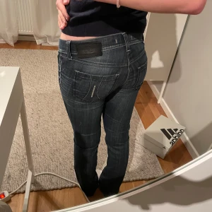 Mörkblå lowwaist jeans - Snygga mörkblå jeans från Fornarina med coola slitningar. De har en super låg midja och en tight passform som framhäver figuren. Perfekta för en trendig look!