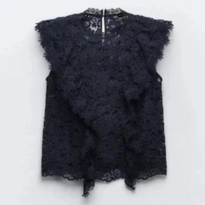 Svart spetsblus - Elegant svart spetsblus med vackra detaljer. Blusen är ärmlös och har en feminin design med spetsmönster över hela plagget. Perfekt för att lägga till en touch av elegans till din outfit.