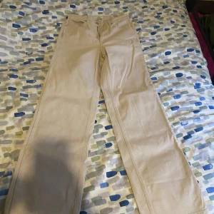 Beige byxor från ONLY - Snygga beige byxor från ONLY i en klassisk straight stil. De har en hög midja och är perfekta för en stilren look. Byxorna är tillverkade i ett bekvämt material som passar bra till vardags.