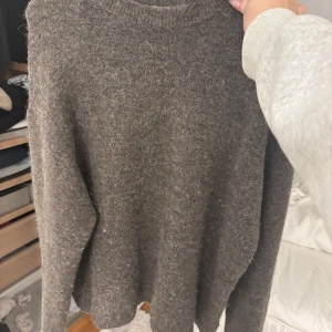 Grå stickad tröja - Mysig brun stickad tröja med långärmad design. Perfekt för kyligare dagar och ger en avslappnad look. Passar bra till jeans eller kjol för en stilren outfit.