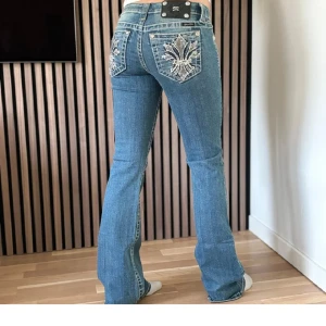 Blå jeans med broderade detaljer - Snygga blå jeans från Miss Me med unika broderade detaljer på bakfickorna. De är bootcut och lågmidjade. I fint skick men lite slitningar längst ner. Priset är diskuterar.