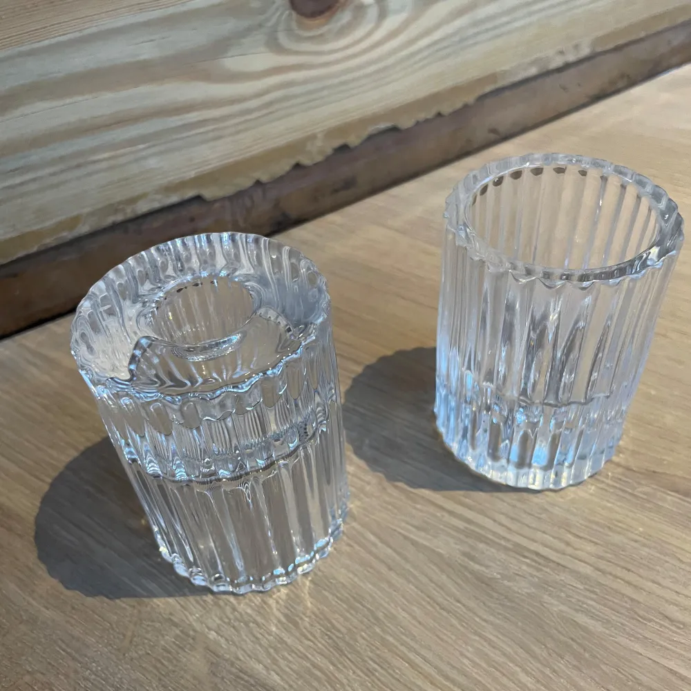 Två stilrena ljuslyktor i klart glas med räfflad design. Perfekta för att skapa en mysig atmosfär i hemmet. Passar utmärkt för värmeljus och ger ett vackert ljusspel.. Asusteet.