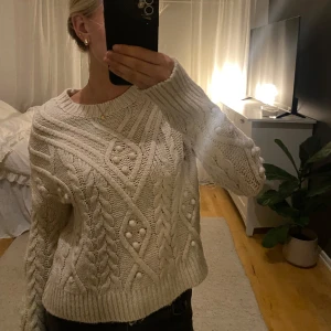 Vit stickad tröja från Camaïeu - Mysig vit stickad tröja från Camaïeu med ett snyggt flätmönster och strukturdetaljer. Tröjan har långa ärmar och ribbade muddar vid ärmslut och nederkant. Perfekt för kyliga dagar! Passar mig som brukar ha Xs. Säljer pga att jag inte använder den så mycket. Hör av dig om du är intresserad! Vi kan diskutera priset!🫶🏻❤️