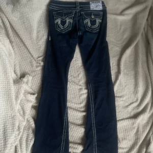 TRUE RELIGION JEANS!!!Mörkblå jeans med kontrastsömmar - Snygga mörkblå jeans med vita kontrastsömmar och dekorativa fickor bak. De har en klassisk femficksdesign och en knappgylf. Perfekta för en avslappnad stil. Ny pris 3300kr
