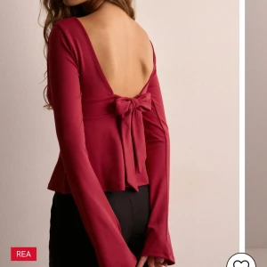 Vinröd topp med öppen rygg och rosett - Snygg vinröd topp med djup v-ringning och lång ärm. Toppen har en elegant öppen rygg med en dekorativ rosett. Jätte fint skick, använd 1 gång