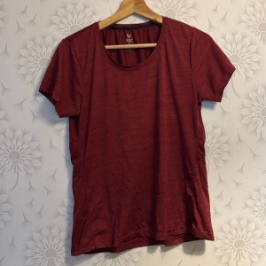 Vinröd  t-shirt från SOC - Snygg röd t-shirt från SOC med rund halsringning och korta ärmar. Perfekt för en avslappnad stil eller träning. Den har en diskret randig textur och en reflekterande detalj på ryggen.