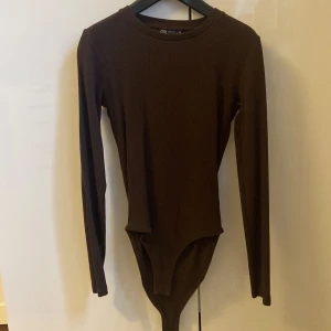Brun långärmad bodysuit från Zara - Säljer en brun långärmad bodysuit från Zara. Nytt skick. Den är mjuk och består av 95% bomull och 5% elastan.  Storlek M