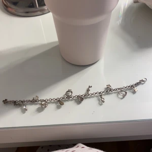 Silverfärgat armband med berlocker -  silverfärgat armband med flera olika berlocker, i fint skick