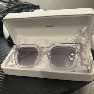   Chimi solglasögon  - Snygga transparenta solglasögon från Chimi med fyrkantig form och mörka linser. Perfekta för en stilren look. Kommer i ett elegant fodral.