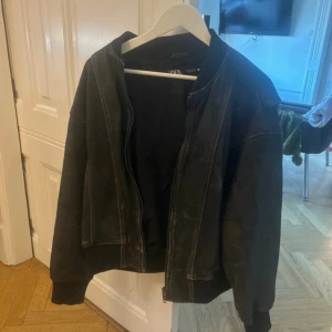 jacka  Zara - Snygg svart bomberjacka från Zara med dragkedja framtill. Jackan har långa ärmar och ribbade muddar vid ärmslut och nederkant. Perfekt för en cool och avslappnad stil. köpt för 800