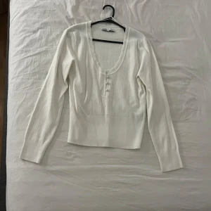Vit ribbad tröja från Zara - En söt vit ribbad tröja från Zara med långa ärmar och knappar framtill. Tröjan har en bekväm passform och är gjord i ett mjukt material. Storlek L men den är lite mindre i storleken så den sitter som en storlek s-m skulle ja säga. Aldrig använts och är i mycket bra skick, köparen står för frakten 