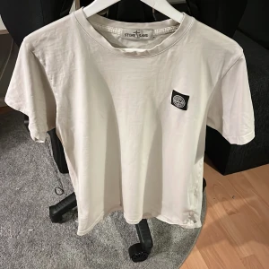 Stone Island T-Shirt  - Säljer min vita Stone Island T-Shirt som inte kommer till användning längre. Köpt för 1600 men säljer för 700 på grund av hålen på övre delen av tröjan, se bild. Passar även S. 