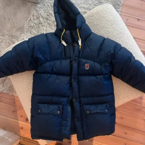 Mörkblå dunjacka från Fjällräven - Säljer en mörkblå dunjacka från Fjällräven. Jättebra skick men har ett litet hål bakom huvan som lätt går att fixa. Pris går att diskutera❤️unisex