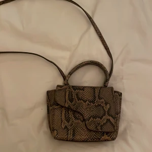 Ormmönstrad axelväska från ATP Atelier - Snygg ormmönstrad axelväska från ATP Atelier. Väskan har en elegant design med magnetlås och en lång axelrem. Perfekt för att ge din outfit en trendig touch. Den är knappast använd och bra skick! Tyvärr har jag inget kvitto kvar men dustbag finns, pris kan diskuteras! 