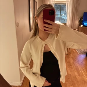 Benvit kofta med knappdetalj - Säljer en stilren beige kofta med en enkel knapp framtill. Koftan har långa ärmar och är perfekt för lager-på-lager-stil. Passar utmärkt till både vardag och mer uppklädda tillfällen. Den är from Gina tricot i storlek s