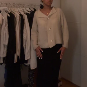 Beige stickad kofta med stora knappar - Mysig beige stickad kofta med stora vita knappar. Perfekt för kyliga dagar med sin avslappnade passform och långa ärmar. En stilren och enkel design som passar till det mesta.