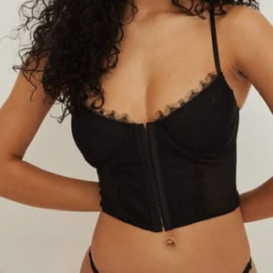 Svart korsett med spetsdetaljer - Snygg svart korsett med spetsdetaljer och ”häften” fram till. Korsetten är från NA-KD i storlek 70C. 💘har tyvärr inga bilder på mig själv för den är för liten.. men kan skicka fler bilder om du vill se närmare osv.. 🥰Priset kan diskuteras ❣️