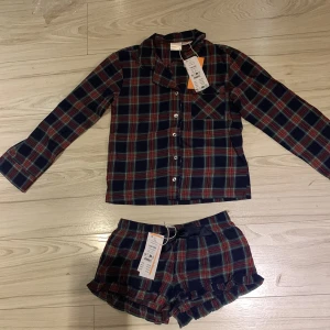 Rutig flanellshorts med volangdetalj - Säljer ett par mysiga flanellshorts i röd och blå rutig design. Shortsen har en söt volangdetalj vid benen och en bekväm passform. Säljer för dom blivit för små💗