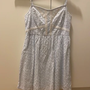 Vit spetsklänning från H&M - Charmig vit klänning från H&M med spetsdetaljer och smala axelband. Perfekt för sommarens varma dagar. Klänningen har en vacker broderad design och en lätt och luftig känsla.