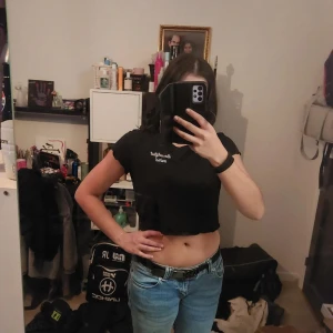 Svart croppad t-shirt - Säljer en svart croppad t-shirt med tryck framtill. Perfekt för en avslappnad stil och passar bra till jeans eller kjol.