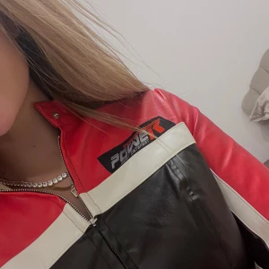 Skinnjacka, F1, bikerjacka - Snygg röd och svart skinnjacka med dragkedja framtill. Jackan har en cool design med vita detaljer och långärmade ärmar. Ger en väldigt snatched midja❤️