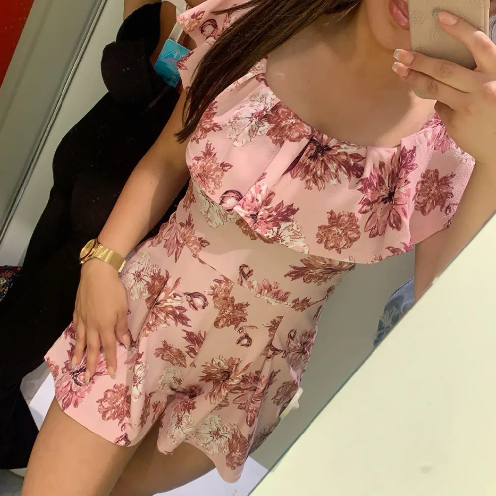 Söt blommig klänning med short i rosa och rött med offshoulder-design och volangdetaljer. strl S. Använd 1-2 gånger. Mekot.