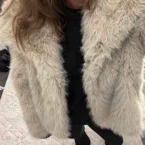 Beige pälsjacka twoangels - Säljer en fluffig och trendig beige pälsjacka med lång ärm. Perfekt för att hålla sig varm och stilren under kyliga dagar. Jackan har en mjuk och lyxig känsla! Helt ny med lappar kvar. Köpt för 1000kr 