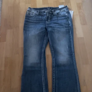 Blå jeans med broderade bakfickor - Snygga blå jeans med bootcut-stil och broderade detaljer på bakfickorna. De har en klassisk femficksdesign och en bekväm passform.