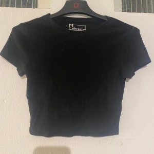 Svart croppad t-shirt - Säljer en svart ribbad croppad t-shirt från Fashion Sister. Den har en rund halsringning och korta ärmar. 