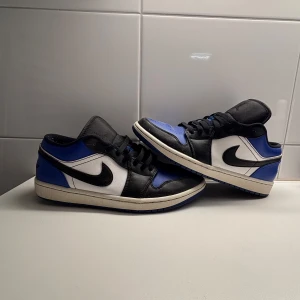 Nike Air Jordans i blått, svart och vitt - Snygga Nike Air Jordans i en fräsch färgkombination av blått, svart och vitt. Skorna har den klassiska Nike-loggan på sidan och snörning framtill. Perfekta för dig som vill ha en stilren och sportig look.