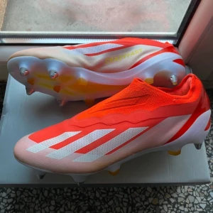 Röda fotbollsskor adidas - Snygga röda fotbollsskor med vita och rosa detaljer. Skorna har en strömlinjeformad design med dobbar för optimalt grepp på planen. Perfekta för den som vill sticka ut på fotbollsplanen. 42,5 ny skick 10/10