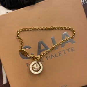 Guldarmband med hängsmycke - Elegant vintage guldarmband från Vivienne Westwood. Armbandet har en fin kedja och ett diskret märke ingraverat på låset. Perfekt för att ge en touch av stil till din outfit. Kollar om det finns något intresse för mitt armband 💕
