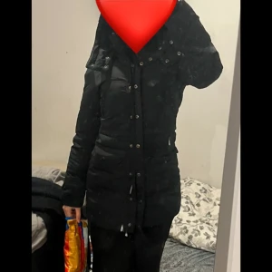Svart dunjacka med knappar - Säljer en stilren svart dunjacka med knappar och dragkedja. Jackan har en figurnära passform och långa ärmar, perfekt för kyliga dagar. Den är både praktisk och snygg, idealisk för vintersäsongen.