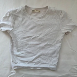 Vit ribbad t-shirt - Säljer en stilren vit ribbad t-shirt från pull & bear. Den har en klassisk rund hals och korta ärmar, perfekt för en enkel och fräsch look.